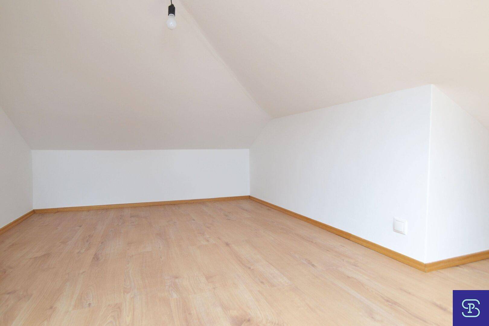 Einfaches Dachgeschosszimmer mit Laminatboden und weißen Wänden, ideal als Abstell- oder Hobbyraum.