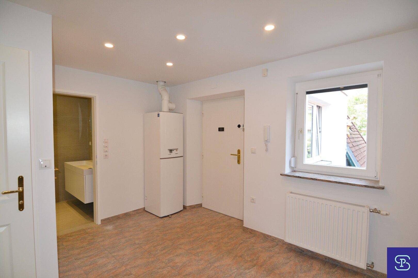 Eingangsbereich mit Fliesenboden, Fenster, Heizkörper und offenem Zugang zum modernen Badezimmer.