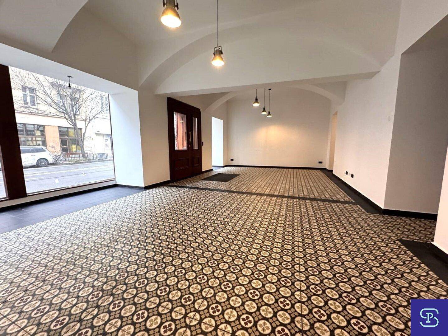 Heller Gewerberaum mit großen Schaufenstern zur Straße und dekorativen Bodenfliesen.