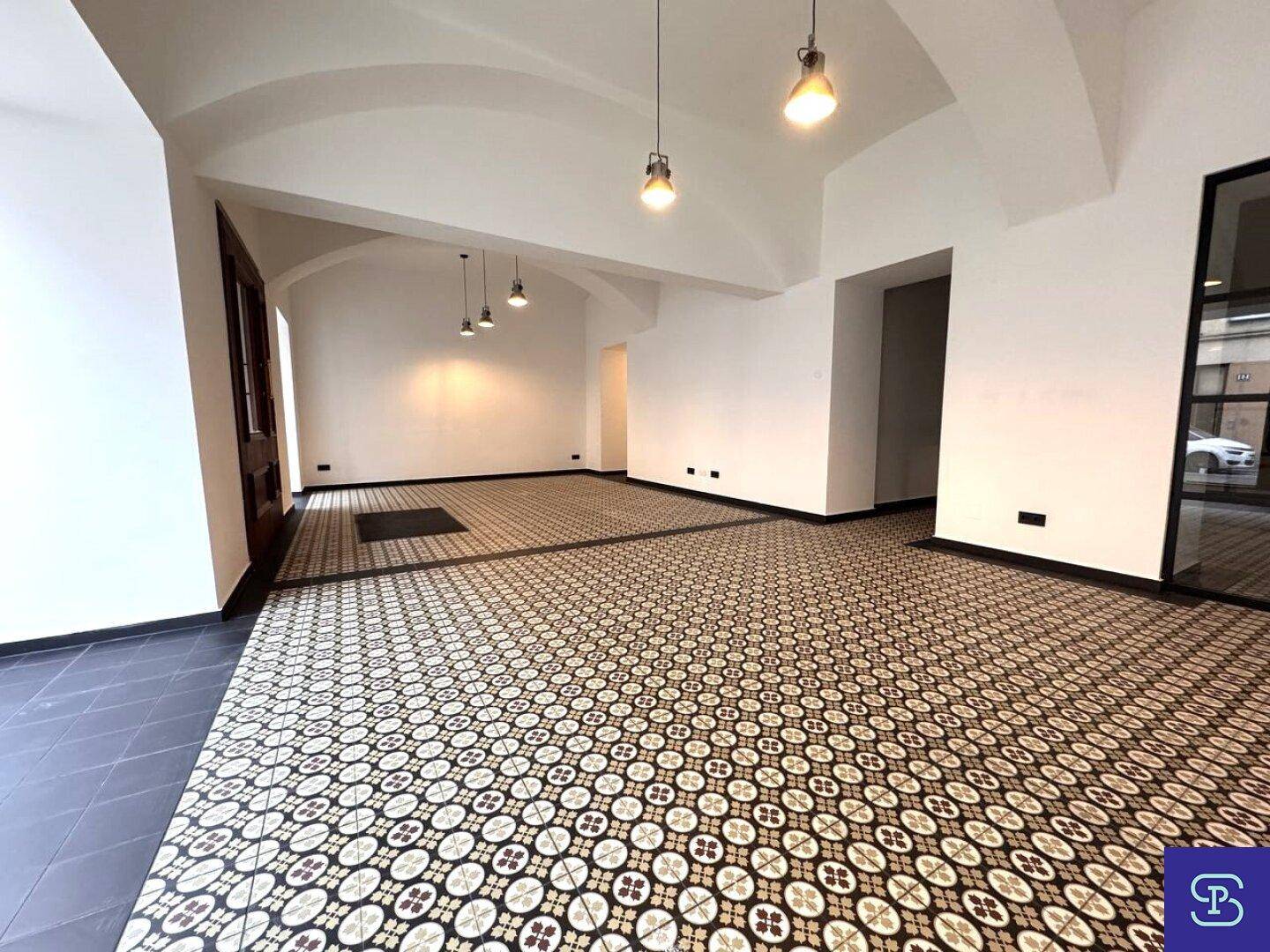 Weitläufiger Gewerberaum mit hohen Gewölbedecken und auffälligem Fliesenbodenmuster.