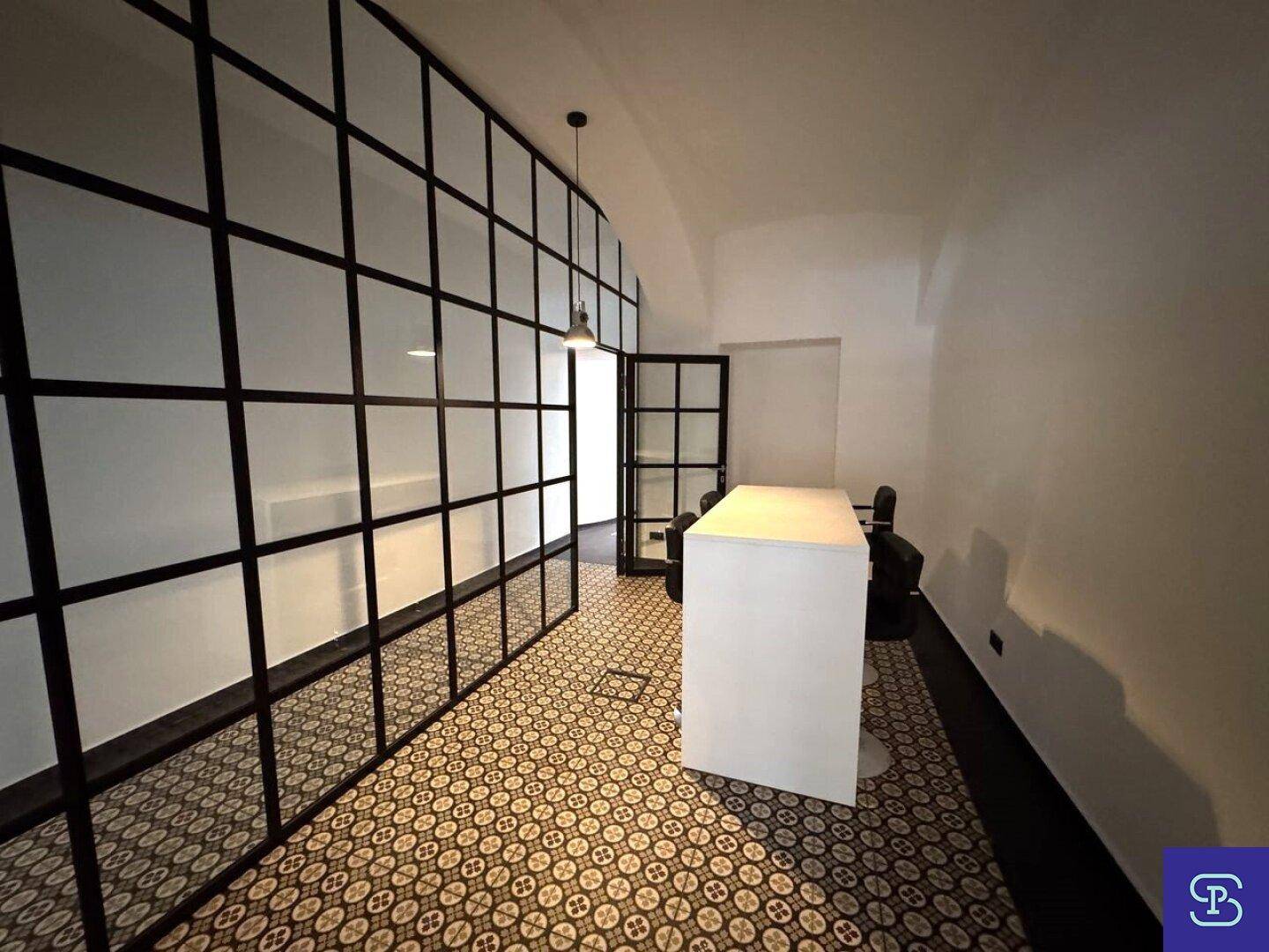 Funktionaler Bürobereich mit Glas-Stahl-Trennwänden und einem großen Arbeitstisch.