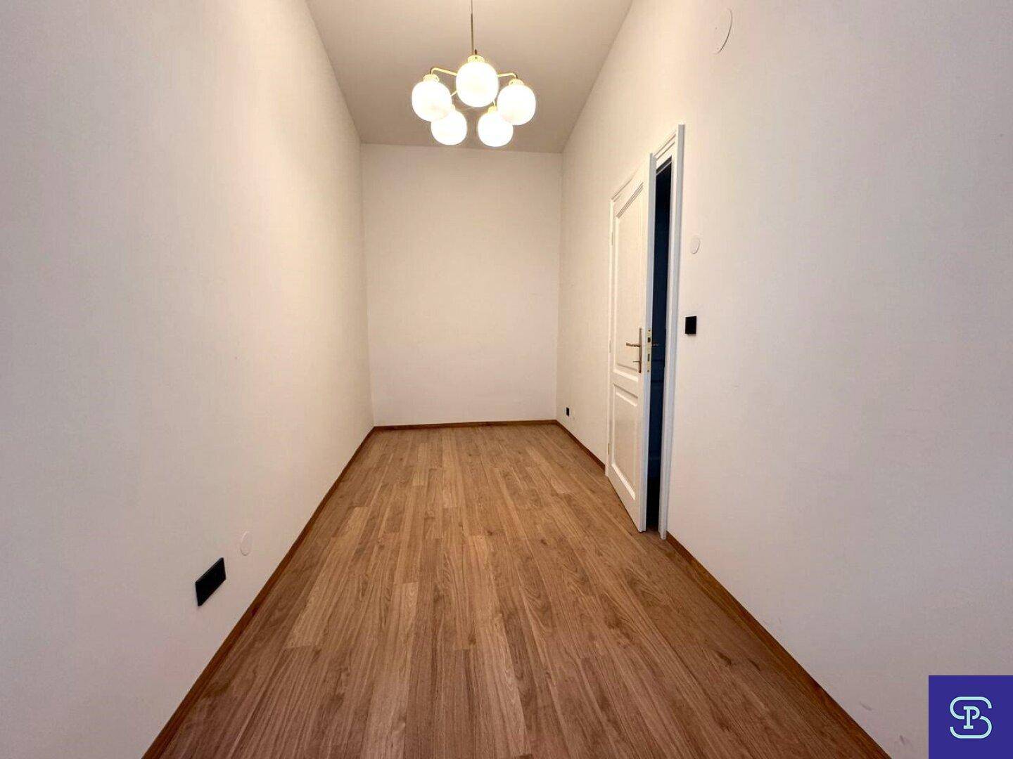 Schlichter Raum mit Holzboden und weiß gestrichenen Wänden, bereit zur individuellen Gestaltung.