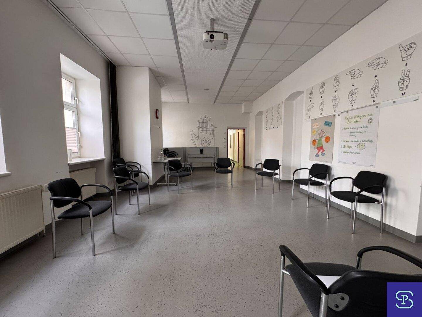 Großer Konferenzraum mit hellem Boden und vielen Stühlen, ideal für Besprechungen und Schulungen.