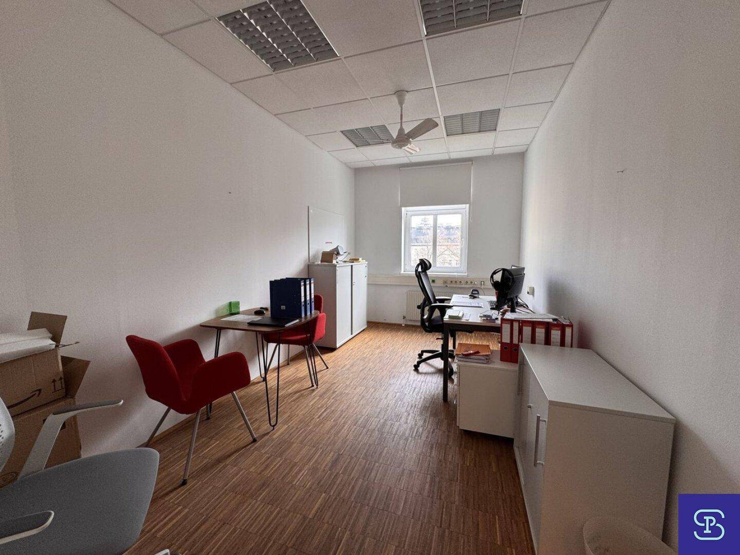 Helles Büro mit Holzparkett, Deckenventilator und zwei Arbeitsplätzen, ausgestattet mit modernen Möbeln.