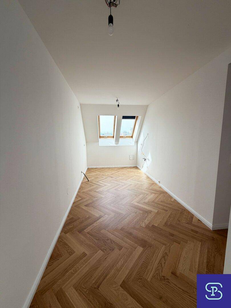 Gemütliches Schlafzimmer im Dachgeschoss mit Fischgrätparkett und zwei Dachfenstern für helles Ambiente.