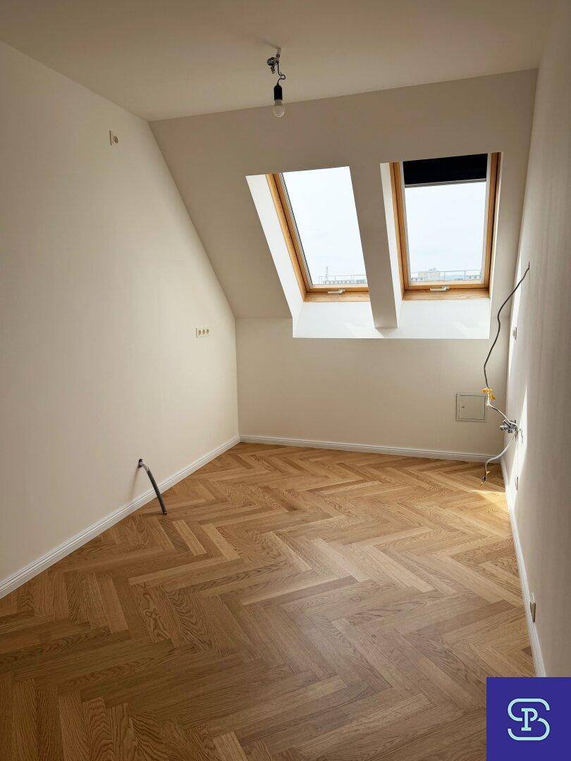 Helles Schlafzimmer im Dachgeschoss mit Fischgrätparkett und zwei Dachfenstern, bereit zur individuellen Gestaltung.