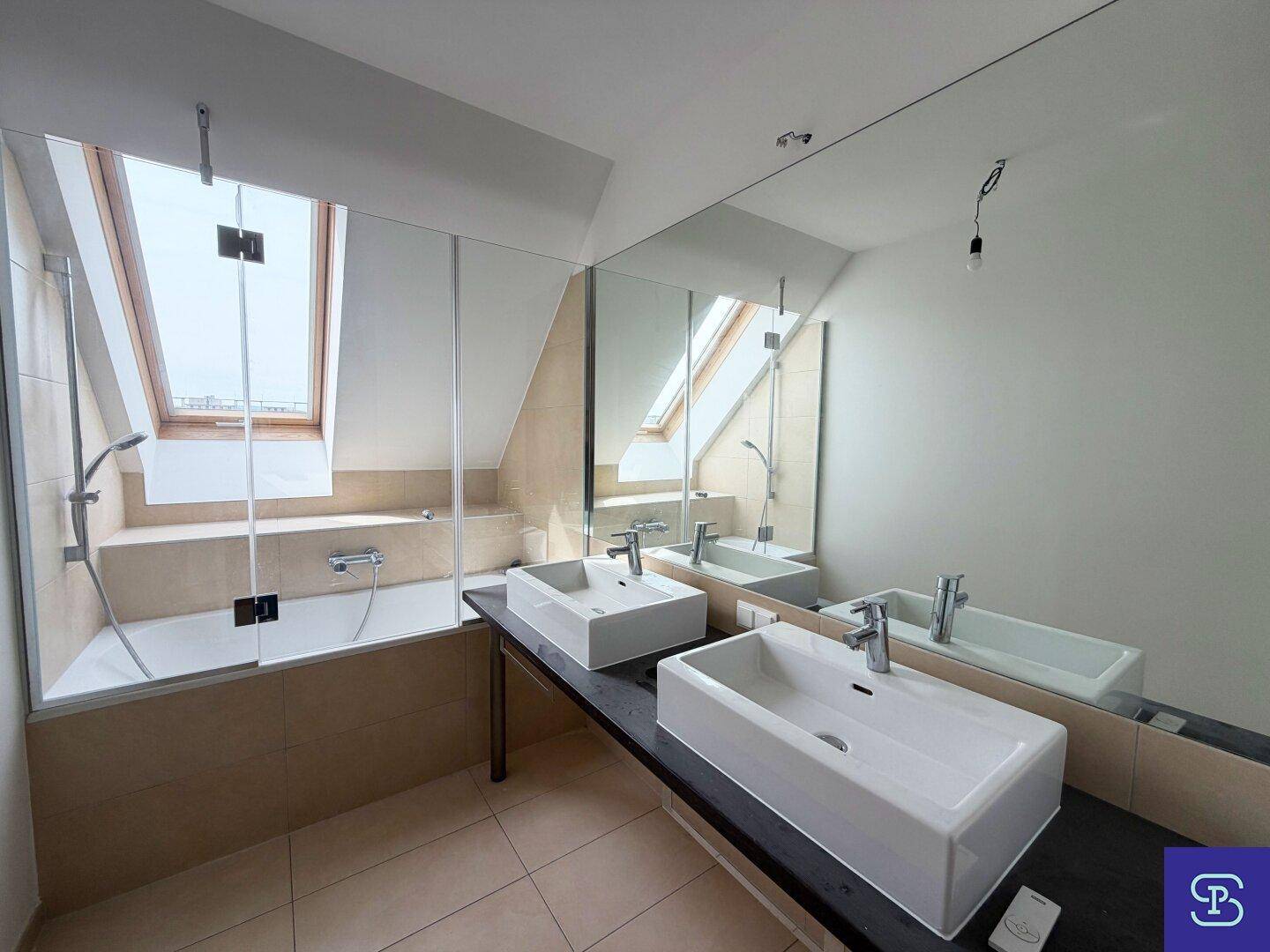 Modernes Badezimmer mit Doppelwaschbecken, Badewanne und Dachfenster für natürliches Licht.
