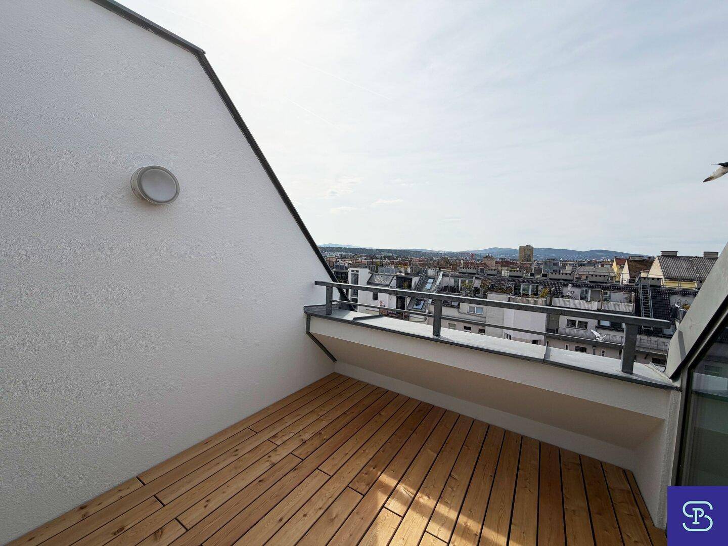 Geräumige Dachterrasse mit Holzboden und weitem Blick über die Stadt, ideal zum Entspannen.
