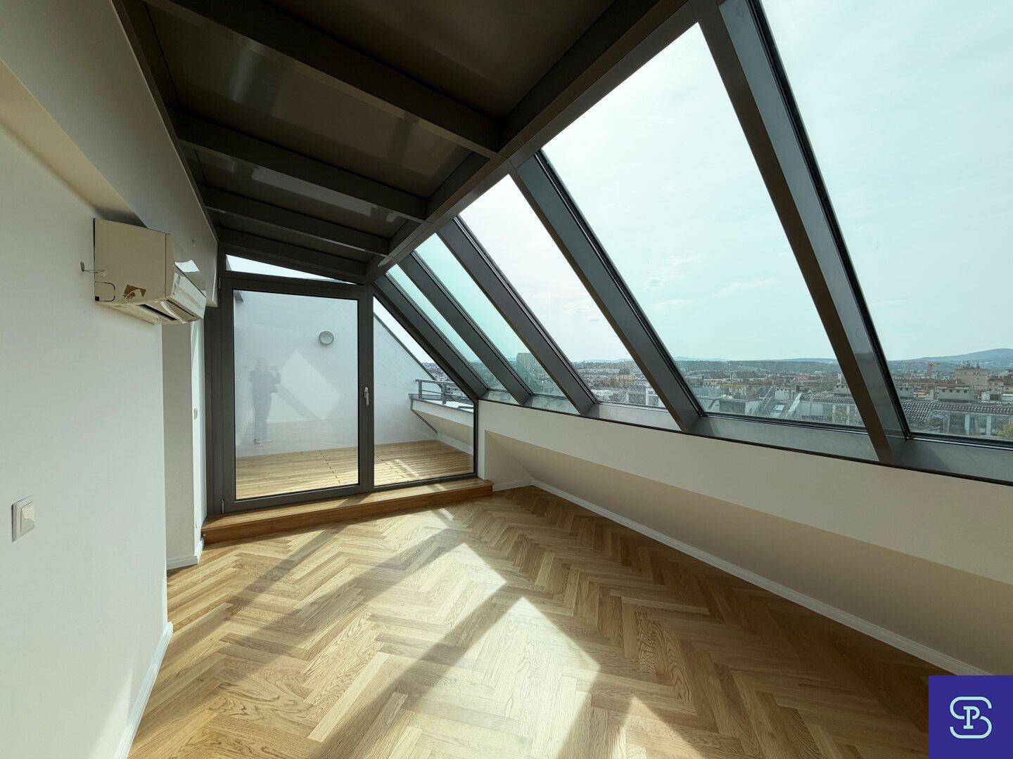 Exklusiver Wohnbereich mit großer Glasfassade, Fischgrätparkett und Zugang zu einer privaten Dachterrasse.