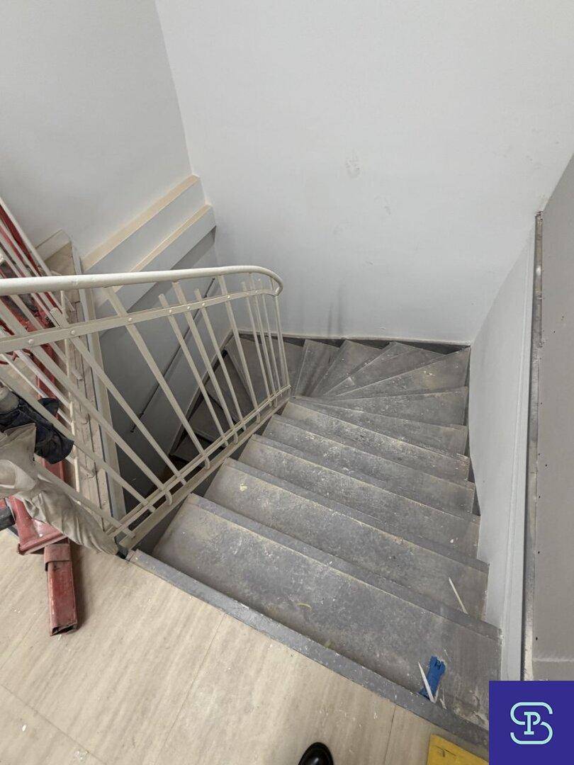 Wendeltreppe mit Metallgeländer und Stufen aus Stein oder Beton, führt in die oberen Stockwerke.