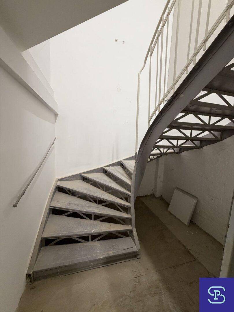 Wendeltreppe mit Metallgeländer und schlichten Stufen, führt zu den oberen Etagen.