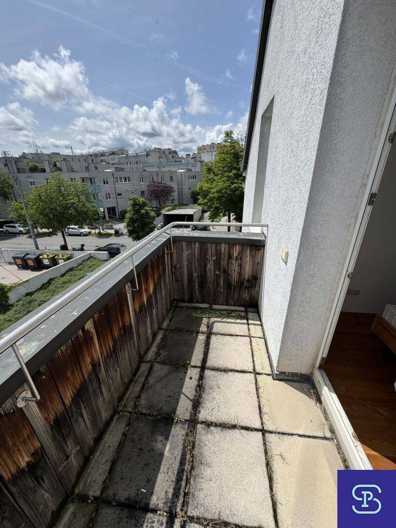 Kleiner Balkon mit Holzwänden und Steinplatten, ideal für frische Luft.