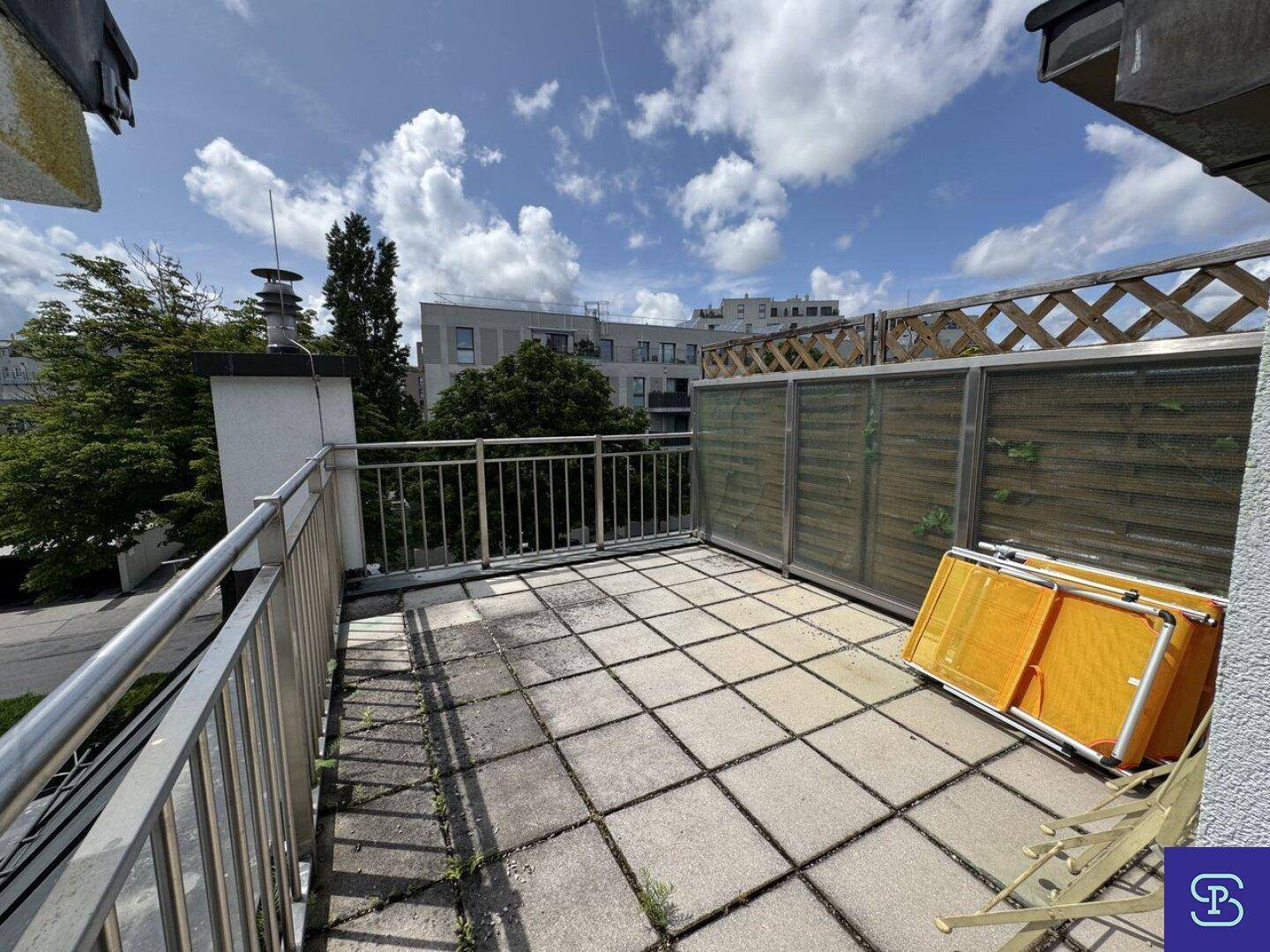 Weitläufige Dachterrasse mit Steinplatten und Sichtschutz, ideal zum Entspannen im Freien.
