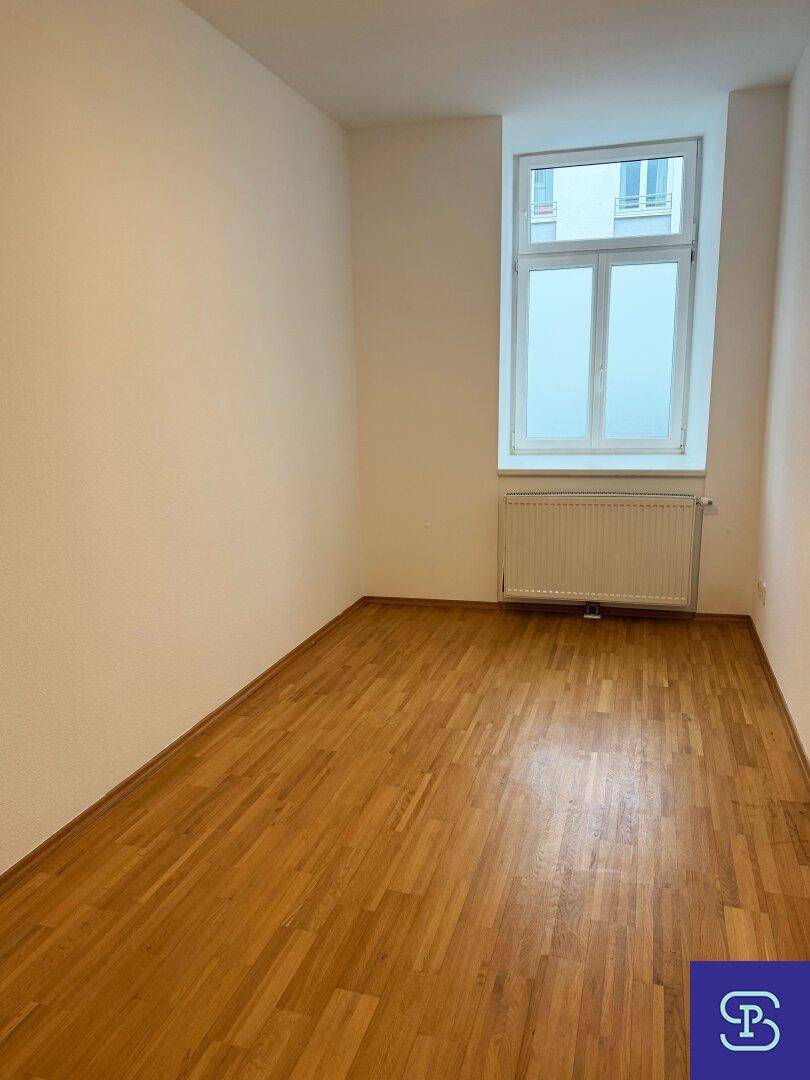 Gemütliches Zimmer mit Parkettboden und einem großen Fenster, das viel Tageslicht hereinlässt.