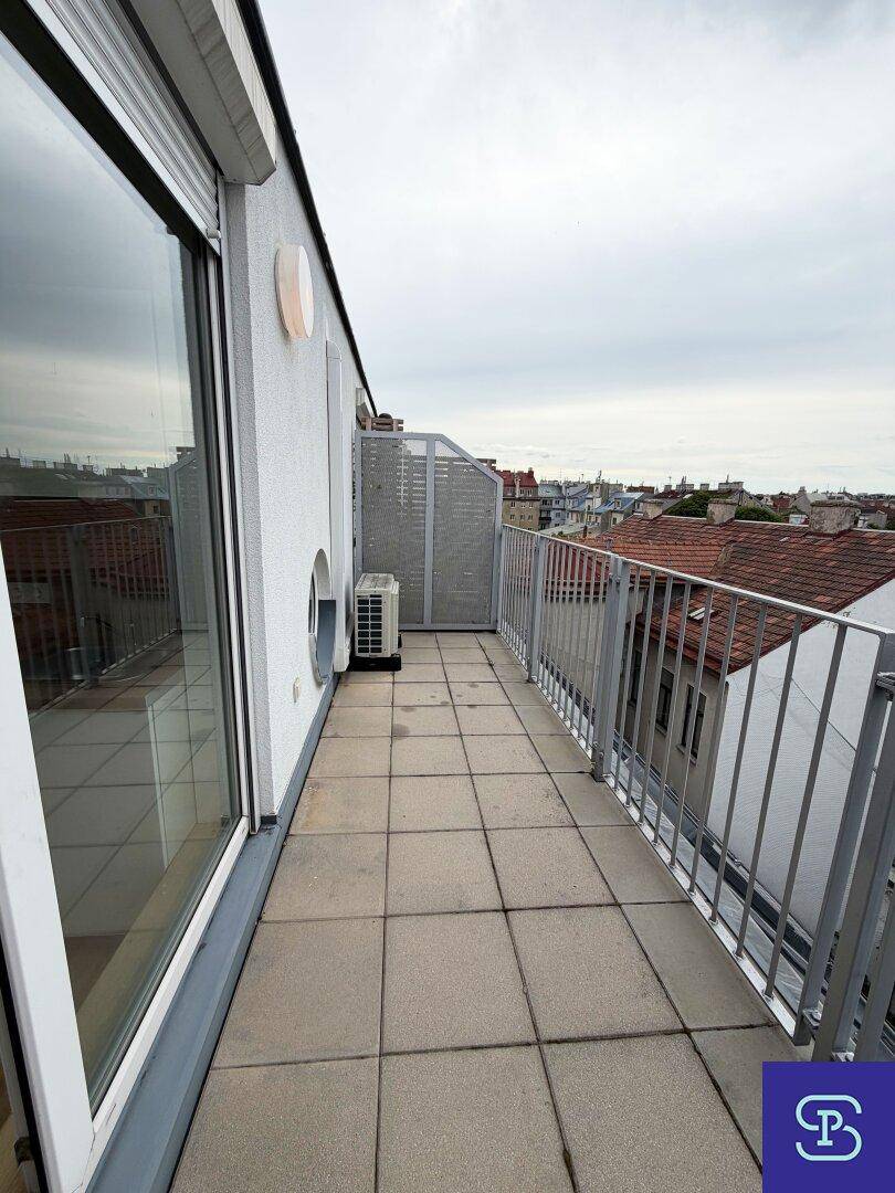 Langer Balkon mit Fliesenboden und Metallgeländer, bietet einen weiten Blick über die Dächer.