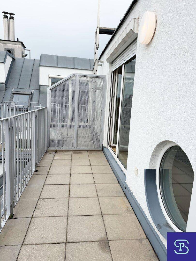 Geräumiger Balkon mit Fliesenboden und Blick auf die umliegenden Gebäude und Dächer.