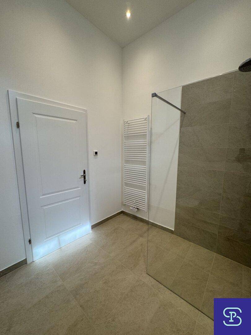 Helles Badezimmer mit begehbarer Dusche und beheiztem Handtuchhalter.