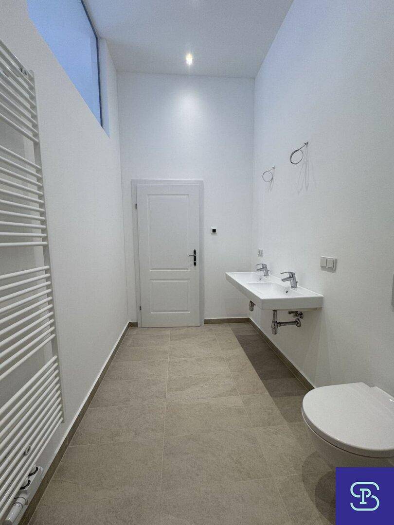 Helles Badezimmer mit Doppelwaschbecken, Wand-WC und beheiztem Handtuchhalter.