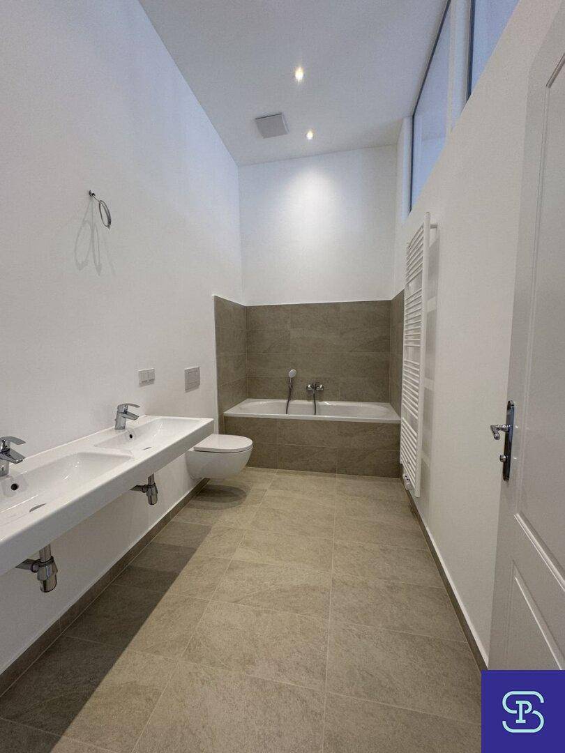 Modernes Badezimmer mit Doppelwaschbecken, Badewanne und beheiztem Handtuchhalter.