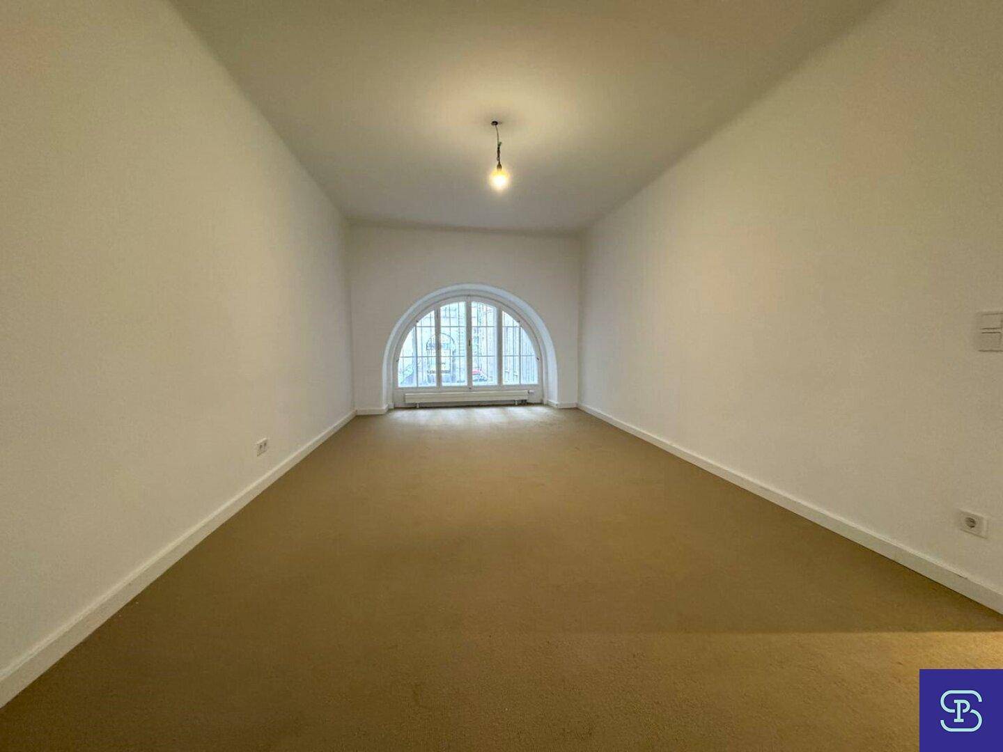 Großes Zimmer mit Teppichboden und einem schönen Rundbogenfenster.