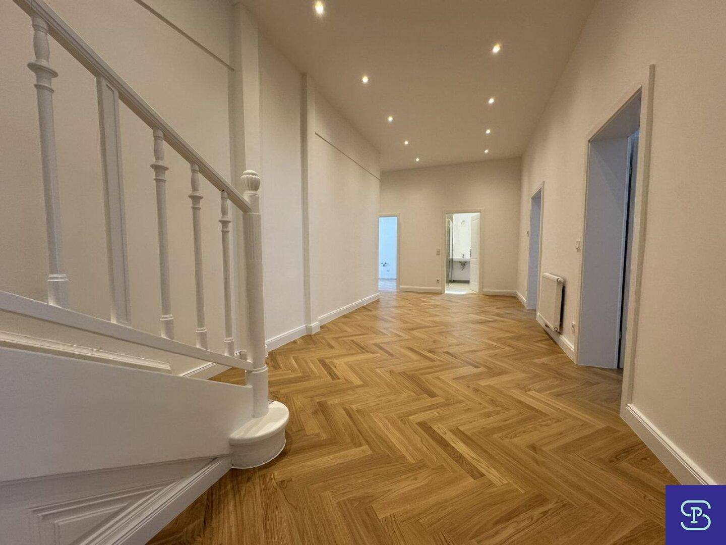 Eleganter Flur mit Fischgrätparkett und einer stilvollen Treppe.