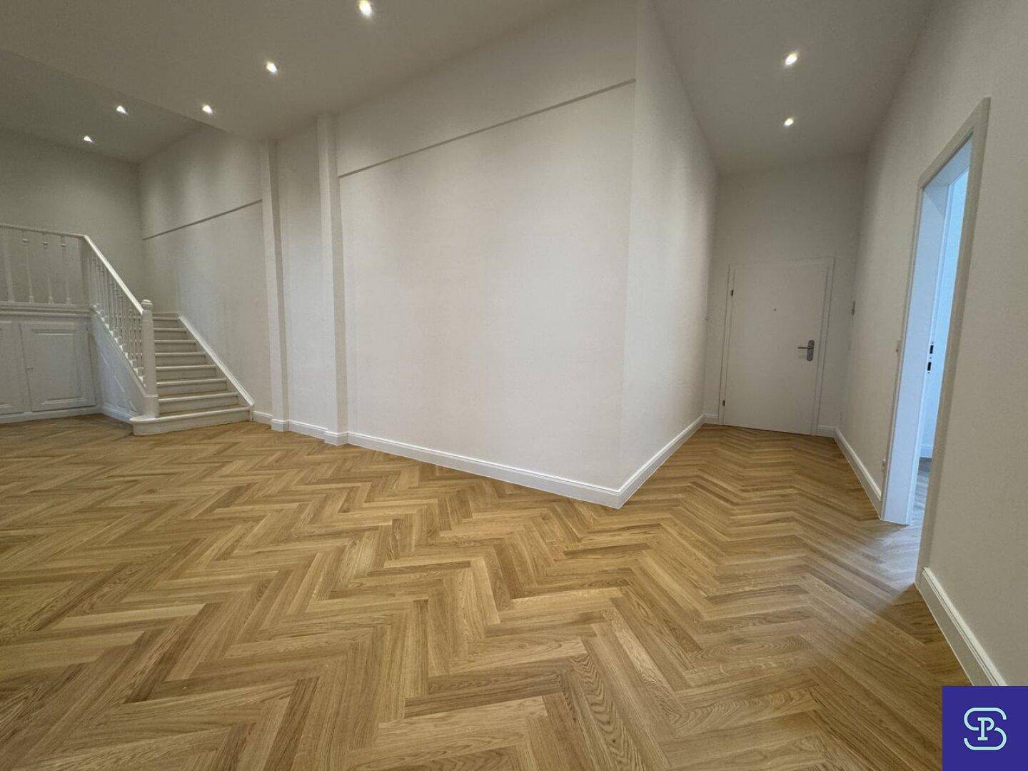 Heller Flur mit Fischgrätparkett und Zugang zu verschiedenen Räumen.