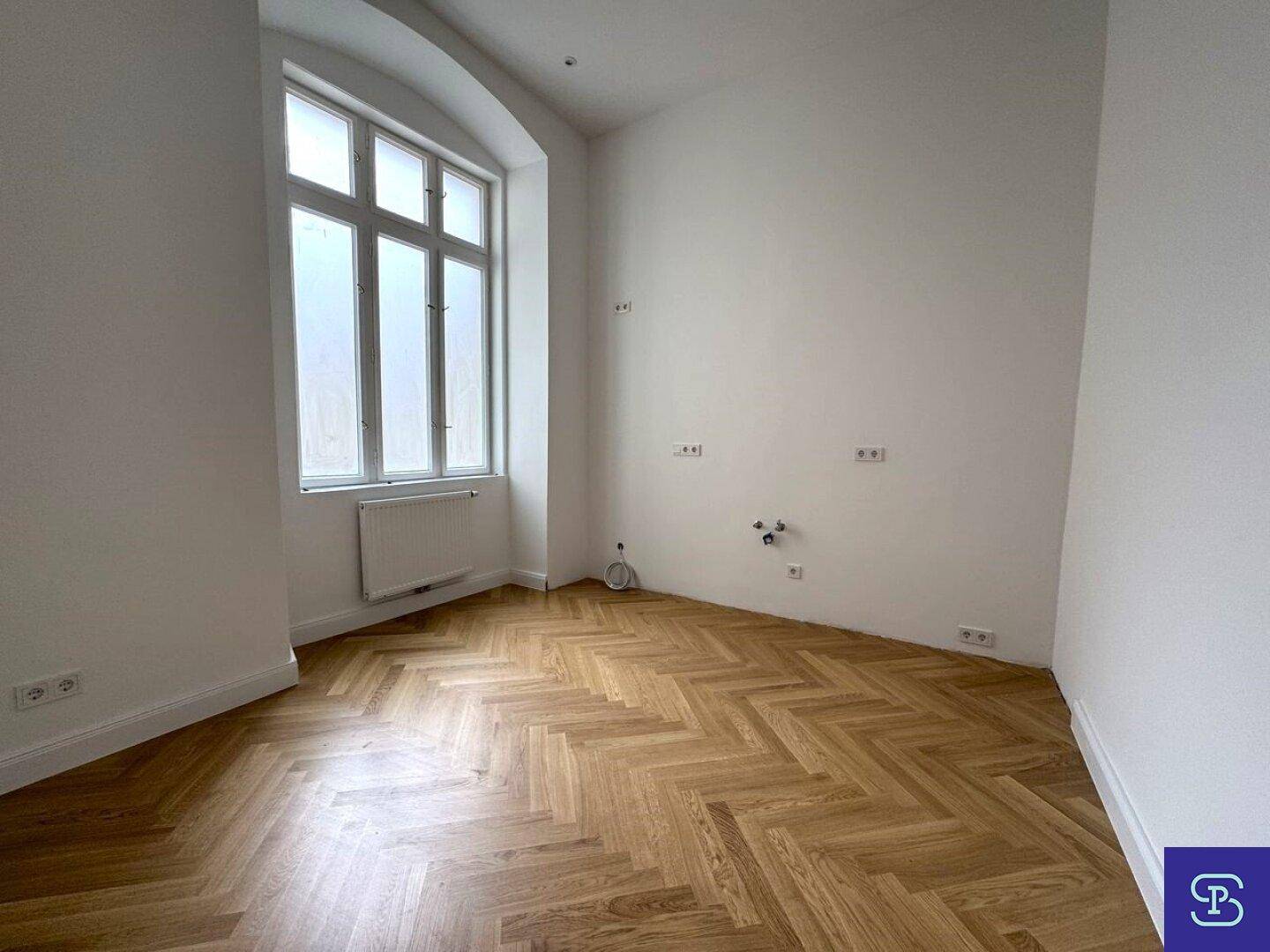 Helle Küche mit Fischgrätparkett und großem Fenster, bereit für die Installation.