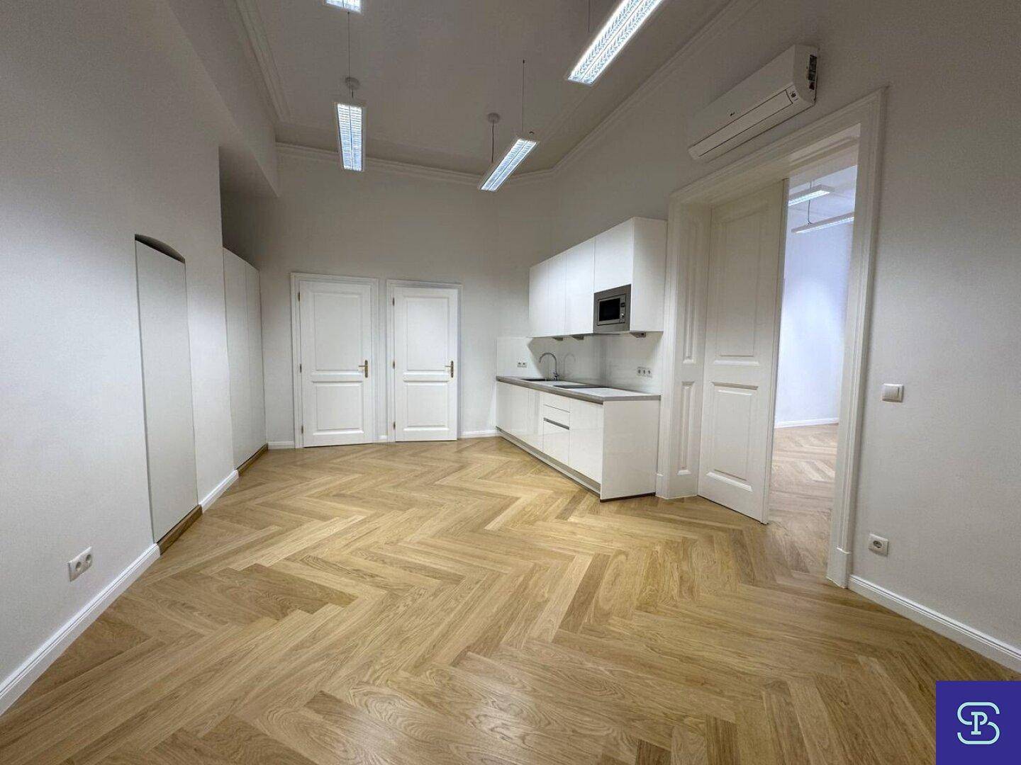 Moderne Küchenzeile mit weißen Schränken, Mikrowelle und Spülmaschine in einem hellen Raum mit Parkettboden.