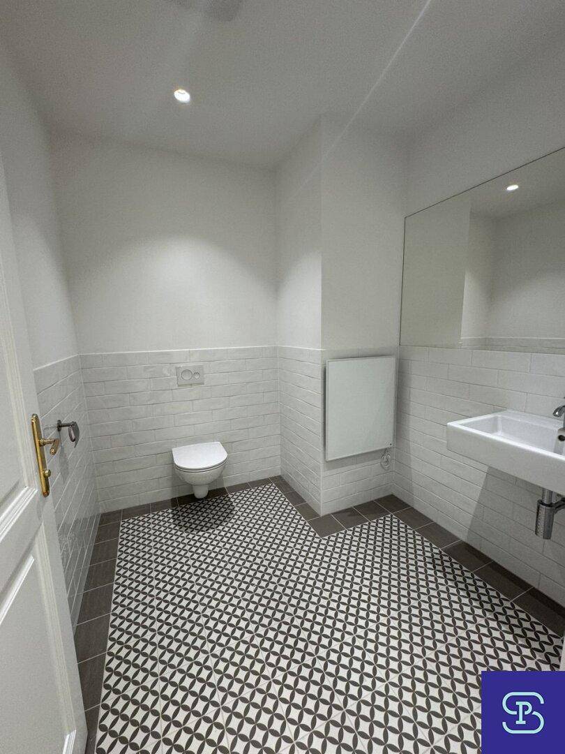 Geräumiges Gäste-WC mit modernem Wand-WC, Waschbecken und auffälligem Fliesenmuster.