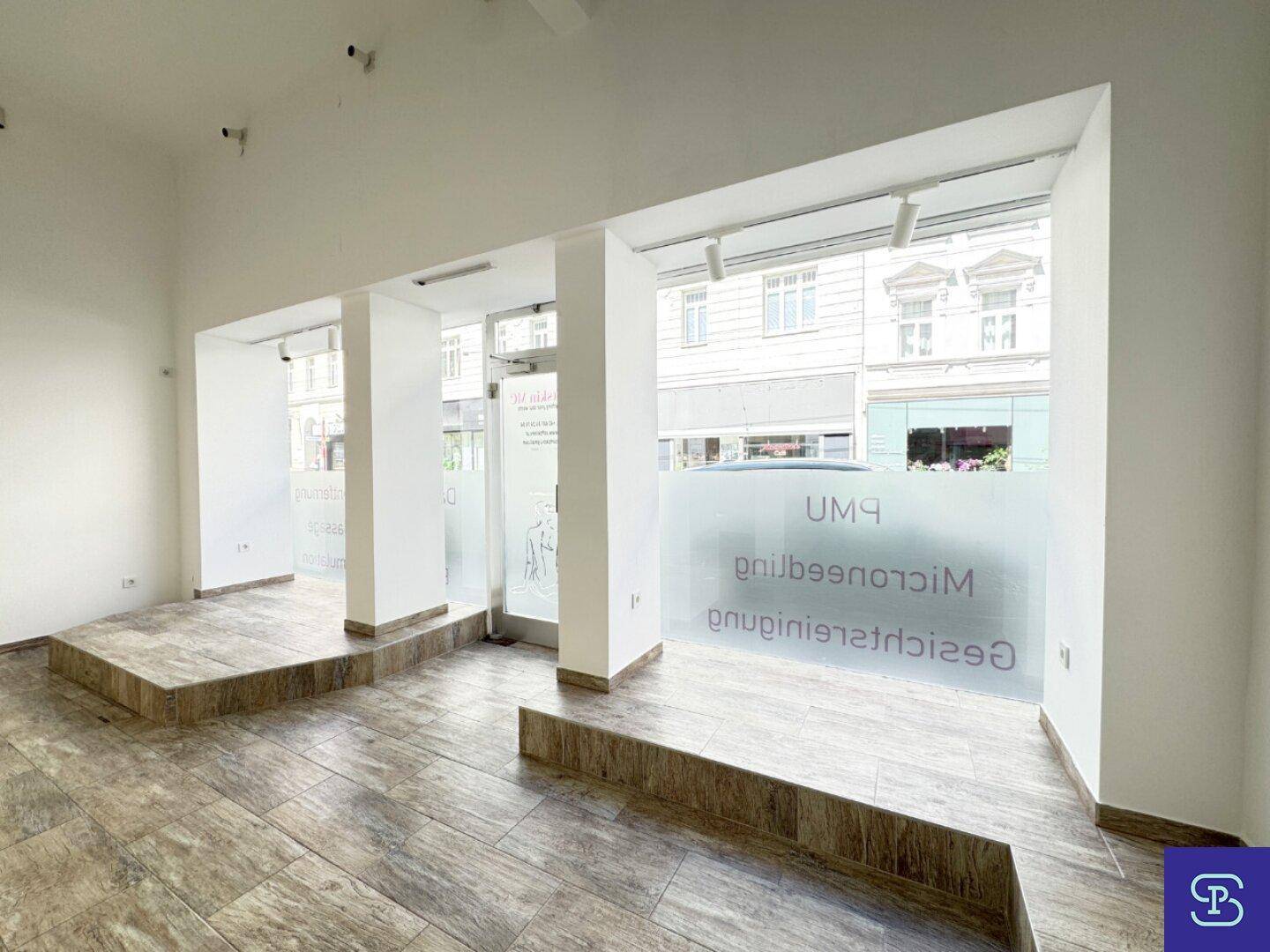 Geräumiger Verkaufsraum mit viel Tageslicht und Blick auf die Straße, ausgestattet mit modernen Deckenleuchten.