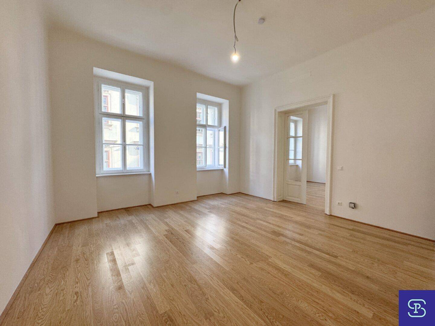 Geräumiges Wohnzimmer mit Holzboden und hohen Fenstern, ideal für helle Wohnkonzepte.