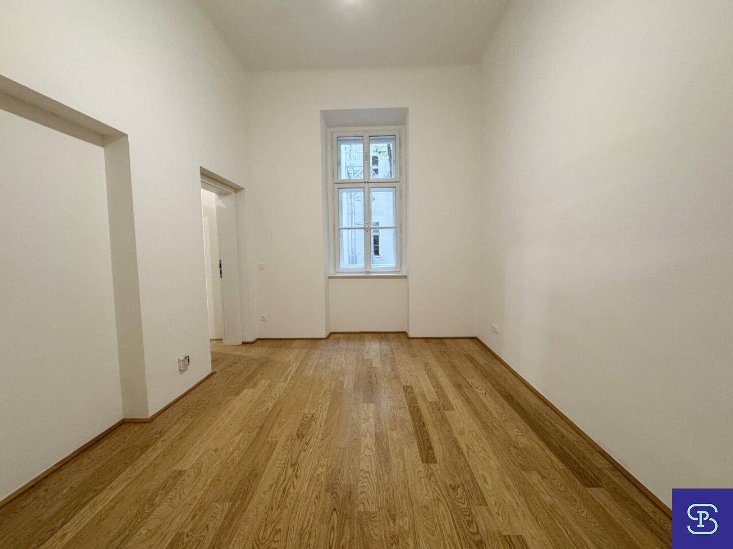 Ruhiges Schlafzimmer mit Holzboden und einem hohen Fenster, bereit zur Einrichtung.