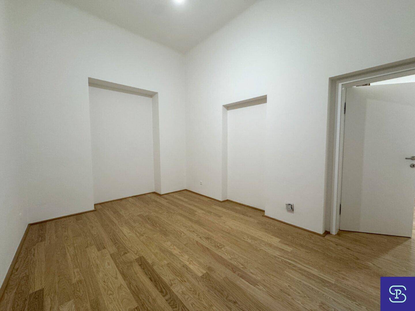 Schlafzimmer mit Holzboden und zwei Nischen, ideal für Einbauschränke oder Dekoration.