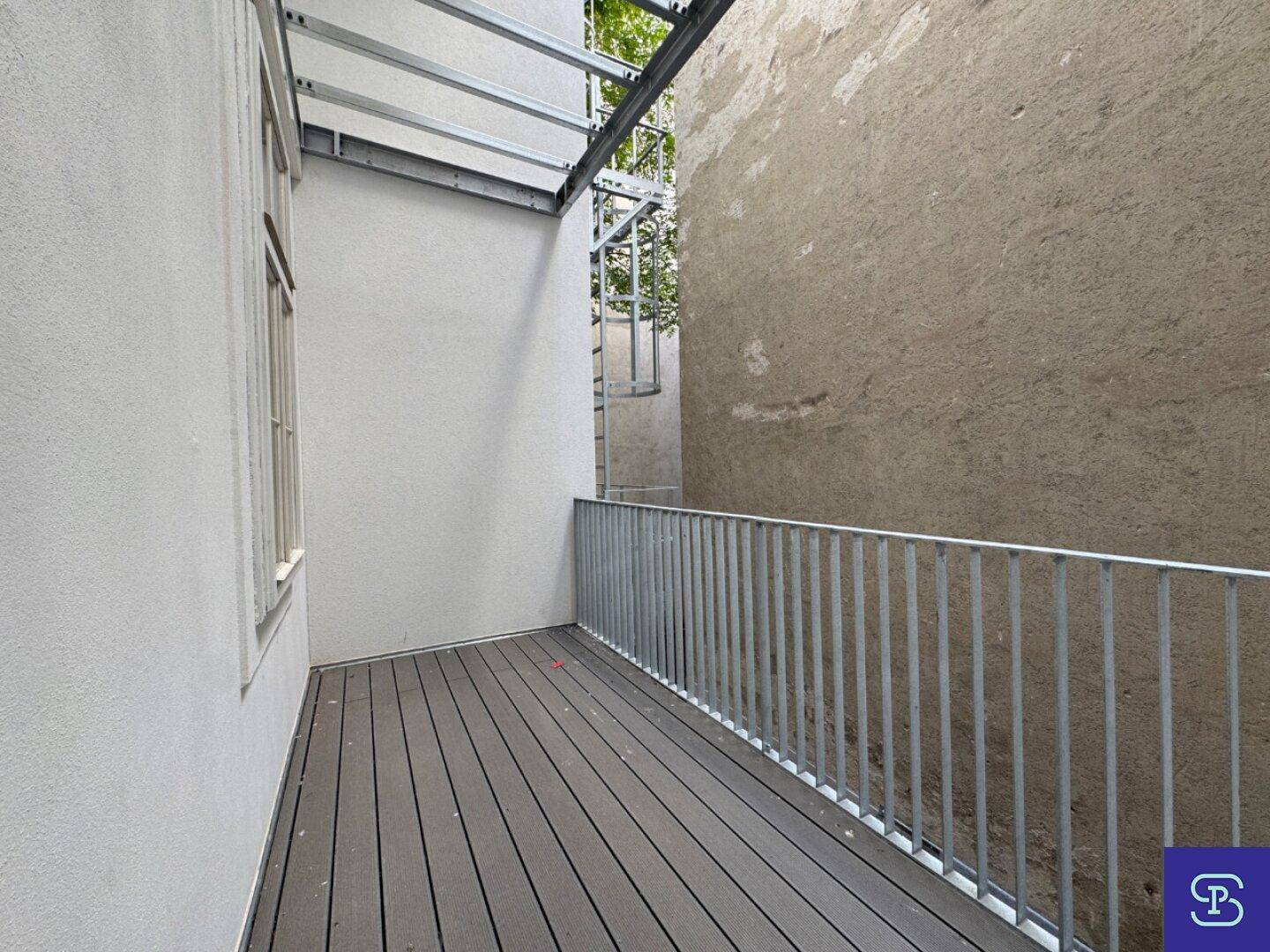 Langer Balkon mit Holzdielen und Metallgeländer, bietet Platz für Entspannung im Freien.