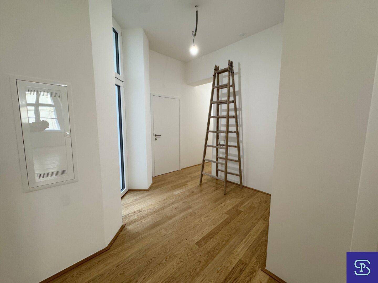 Eingangsbereich mit Holzboden und einer Leiter, die auf die hohe Decke hinweist.