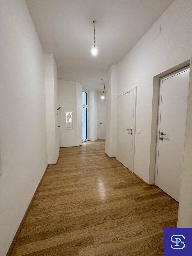 Langer, heller Flur mit Holzboden und mehreren Türen, die zu den Zimmern führen.