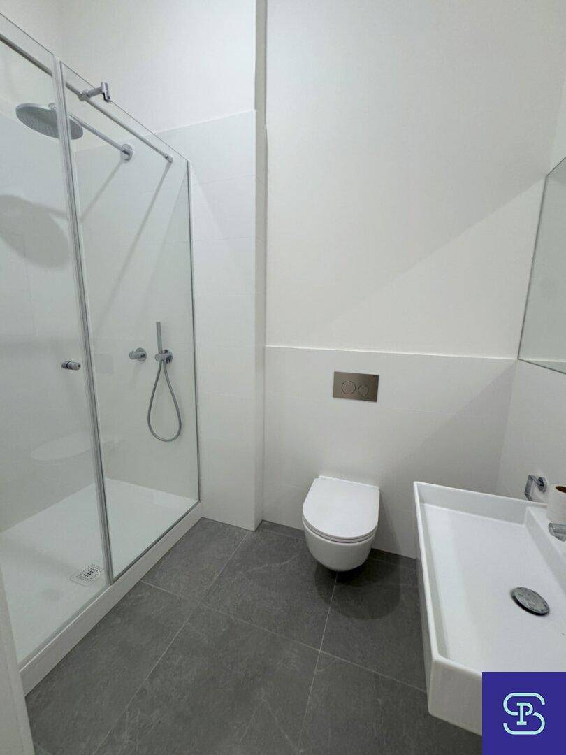 Modernes Badezimmer mit Dusche, wandhängendem WC und Waschbecken, in hellen Tönen gehalten.