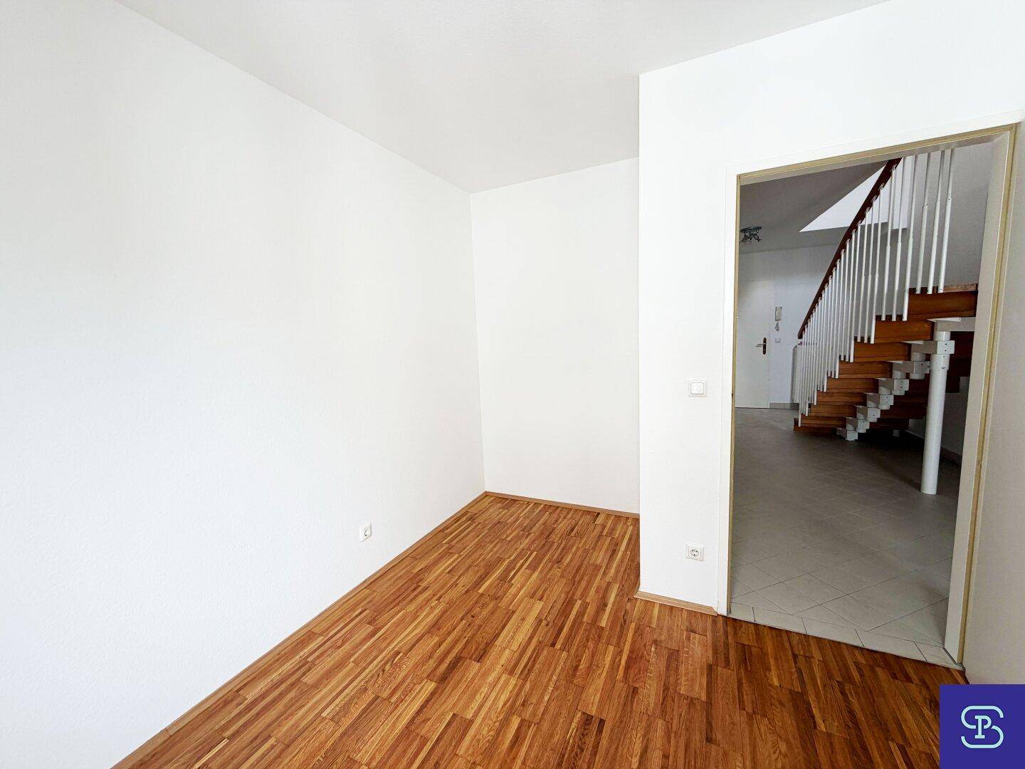 Blick vom Zimmer in den Flur mit Holztreppe und hellem Fliesenboden.