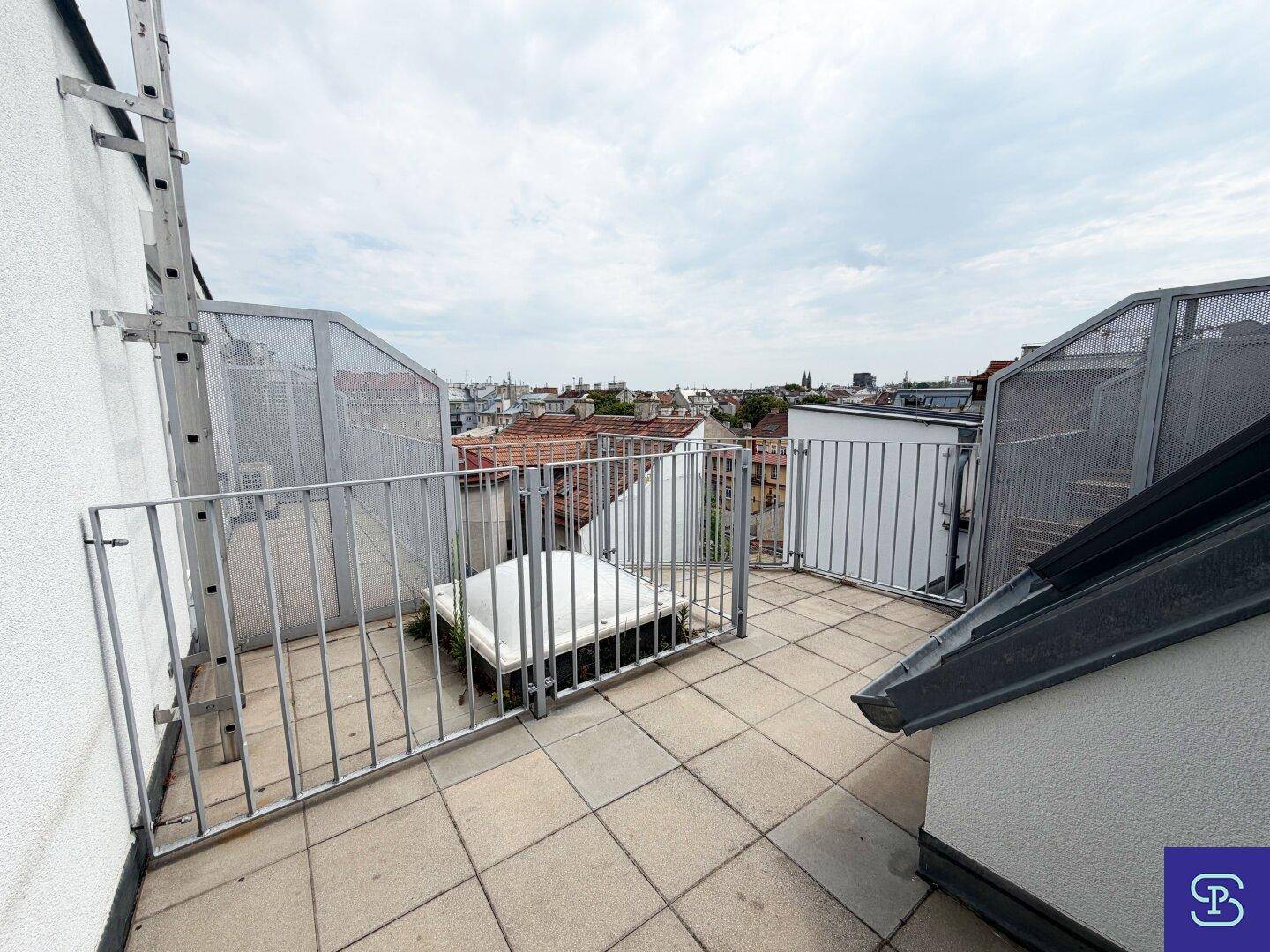 Dachterrasse mit Fliesenboden und Metallgeländer, bietet einen weiten Blick über die Stadt.