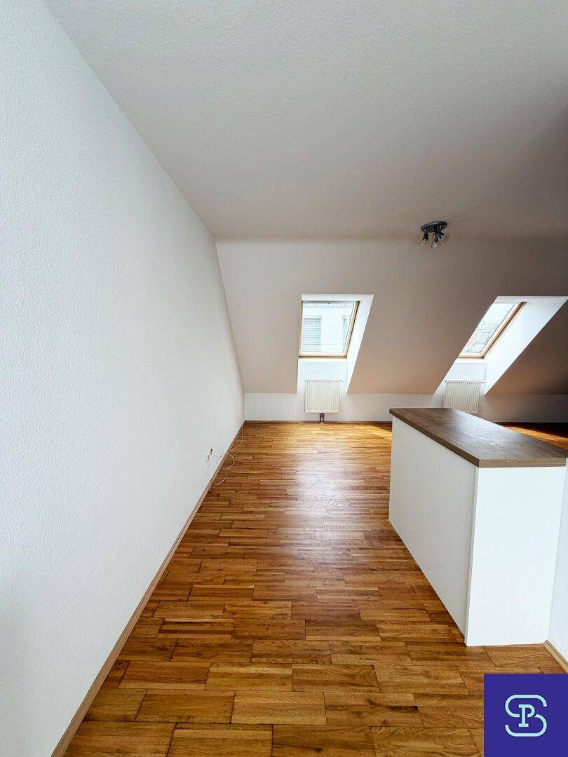 Heller Wohnbereich mit Parkettboden, Dachschrägen und Dachfenstern, offen gestaltet.