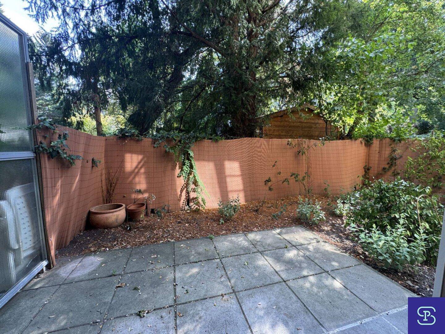 Kleiner Gartenbereich mit gepflasterter Terrasse und umgebender Bepflanzung.