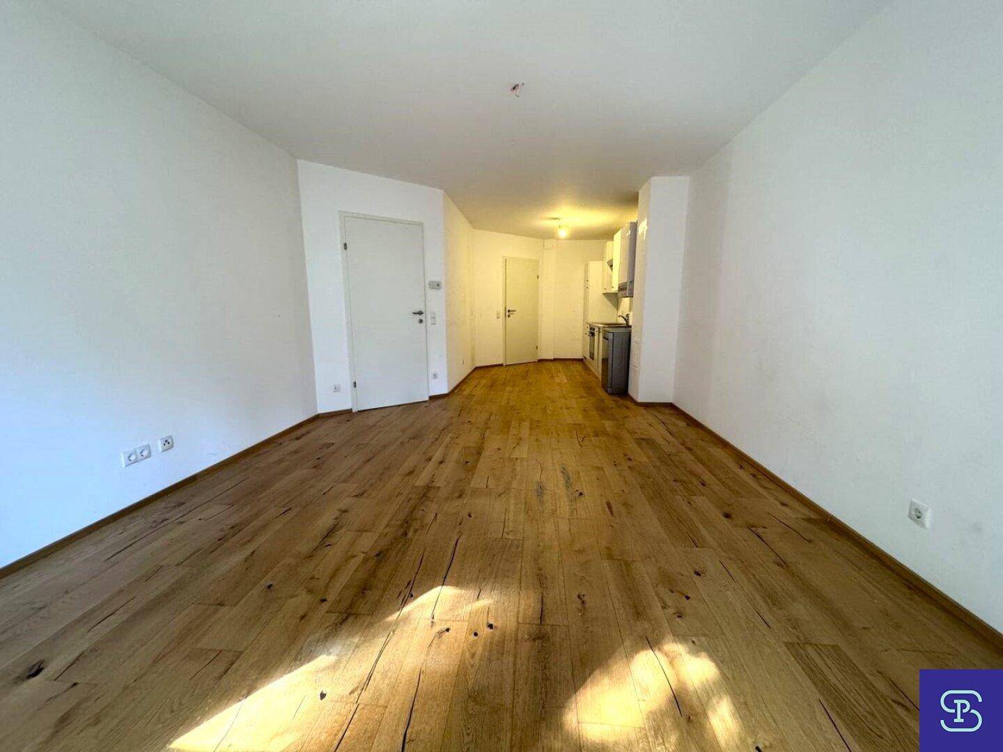 Heller Wohnbereich mit Holzboden und Blick auf den Küchenbereich.