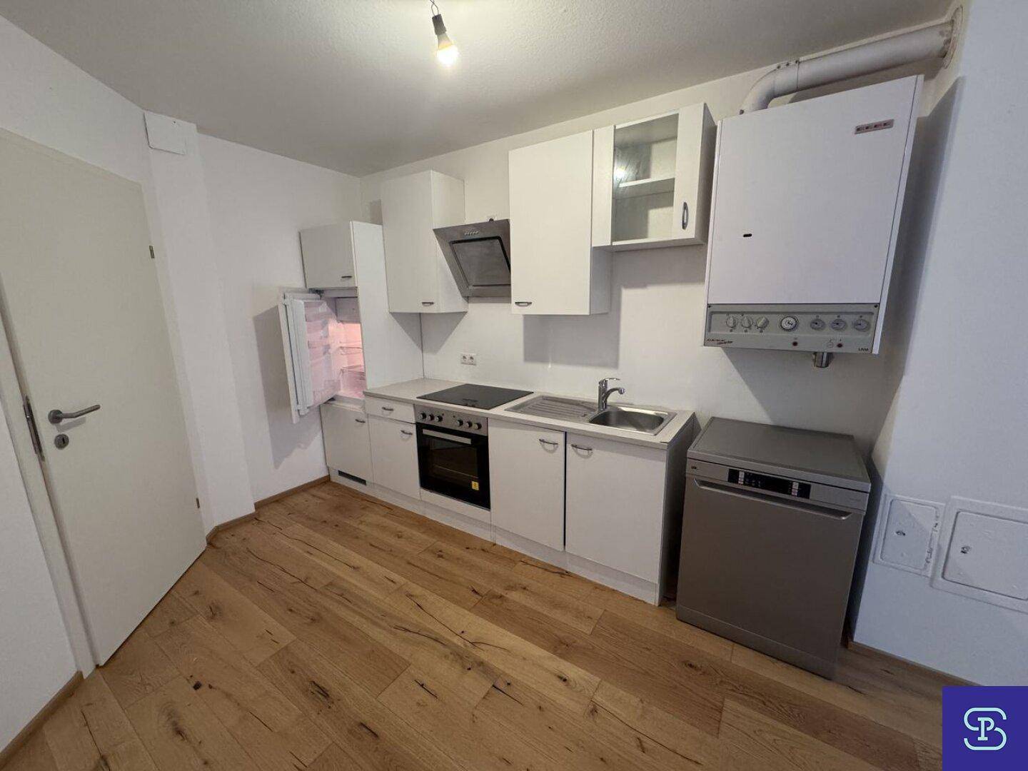 Voll ausgestattete Küche mit weißen Schränken, Kühlschrank und modernen Geräten.