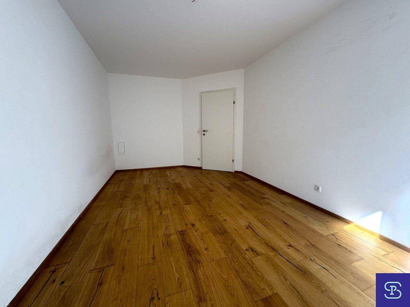 Geräumiges Zimmer mit Holzboden und weiß gestrichenen Wänden.