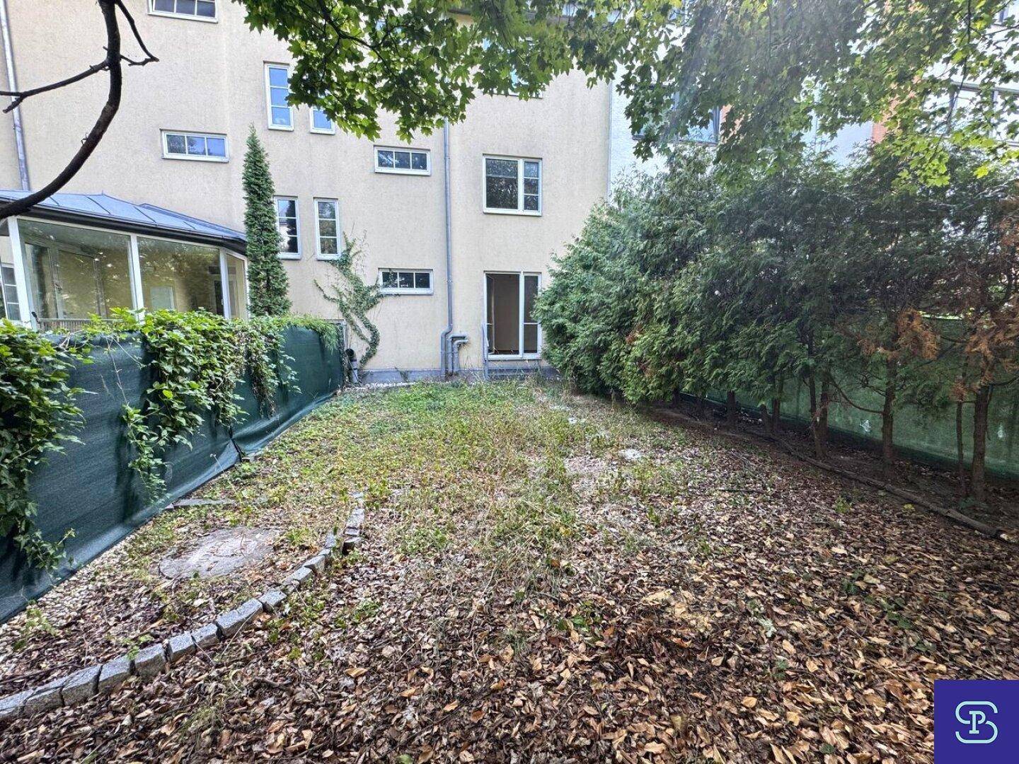 Hinterer Gartenbereich mit Rasenfläche und Blick auf die Gebäudefassade.