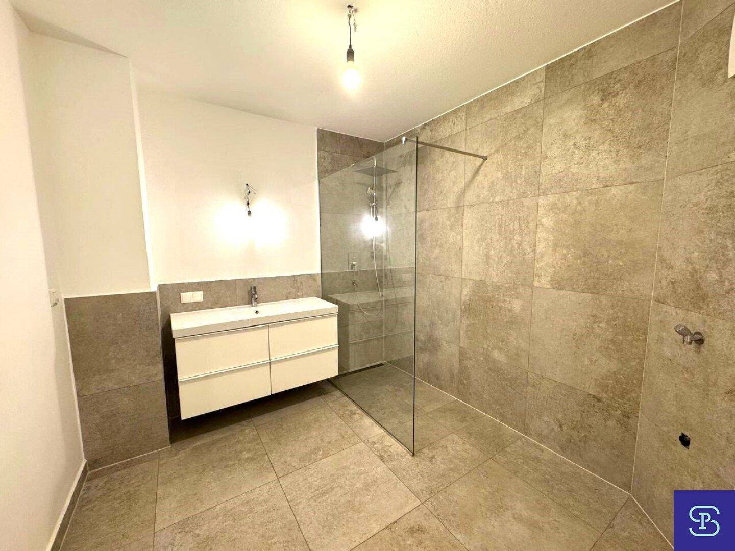 Modernes Badezimmer mit großformatigen Fliesen, Waschtisch und begehbarer Dusche.