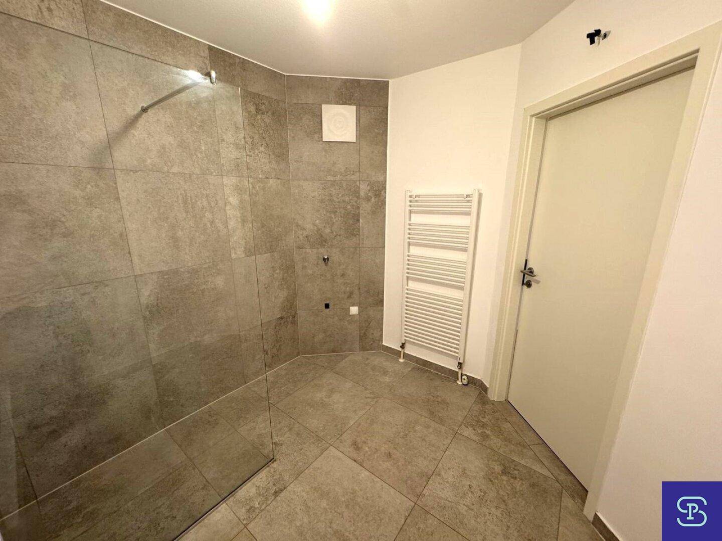 Badezimmer mit begehbarer Dusche, Handtuchheizkörper und modernen Fliesen.