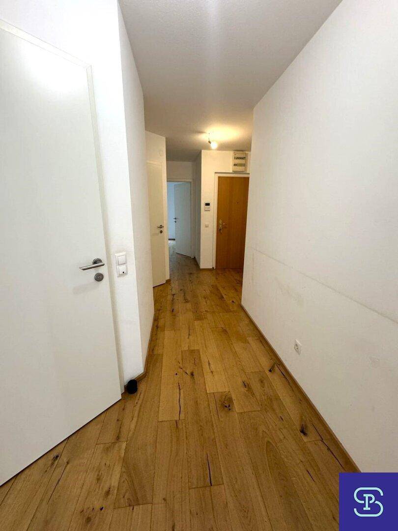 Heller Flur mit Holzboden und Zugang zu verschiedenen Zimmern.