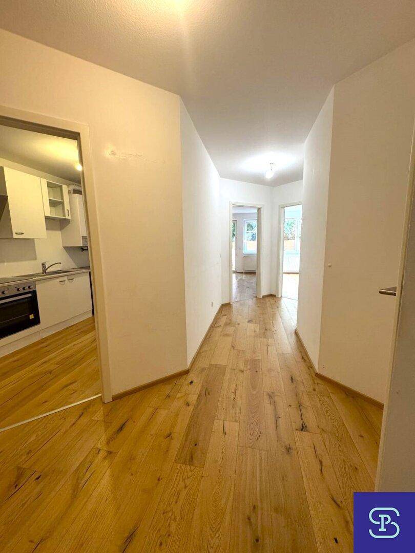 Geräumiger Flur mit Holzboden und Blick in den Küchen- und Wohnbereich.