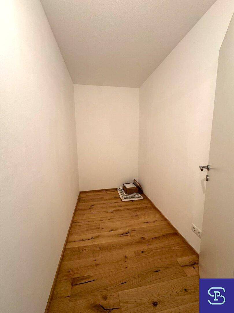 Praktischer Abstellraum mit Holzboden und weißen Wänden.
